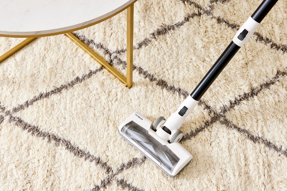 A vacuum cleaner positioned on a rug near a table and chair, illustrating a carpet cleaning service in Honolulu, HI.