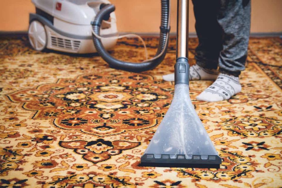 A person operates a vacuum cleaner on a carpet, highlighting a rug cleaning service in Honolulu, HI.
