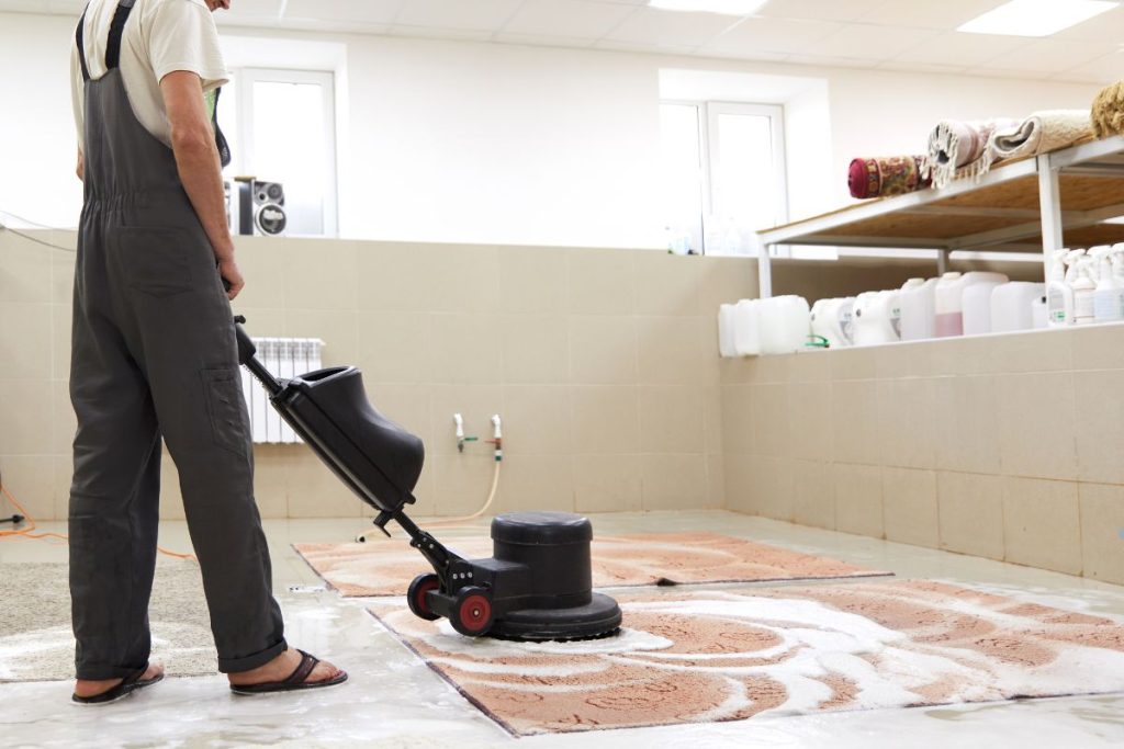 A man using a vacuum cleaner to clean a carpeted room as part of a carpet cleaning service.