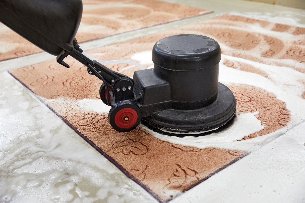 A person vacuuming a carpeted floor, focusing on removing dirt and debris for a clean appearance.